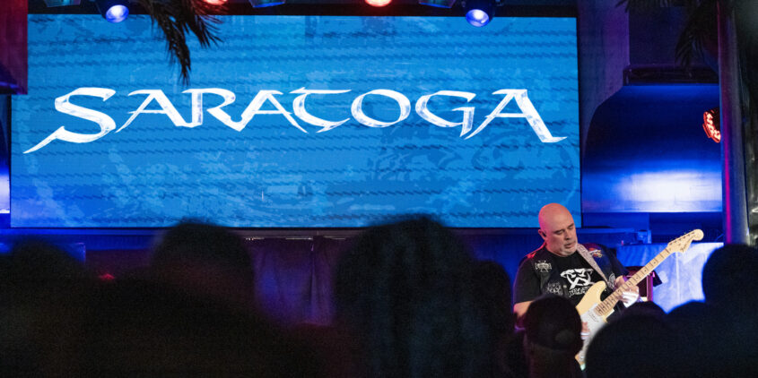 Jero tocando con las letras de Saratoga de fondo